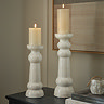 image of two ceramic ribbed pillar candle holders with battery operated candles on a rustic wooden sideboard, in front of a neutral wall with abstract painting hanging behind