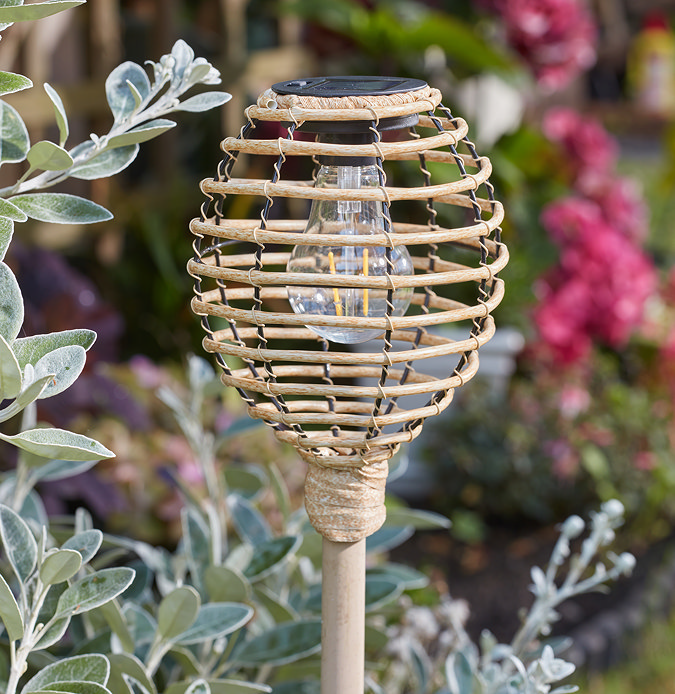 image taken in daylight of top of faux rattan stake light shaped like beehive, with bulb inside