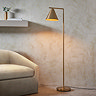 image of tall slim floor light in corner of room with conical head directing warm light onto floor and the armchair next to it