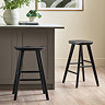 image of black oak bar stool against grey kitchen bar, on wooden flooring