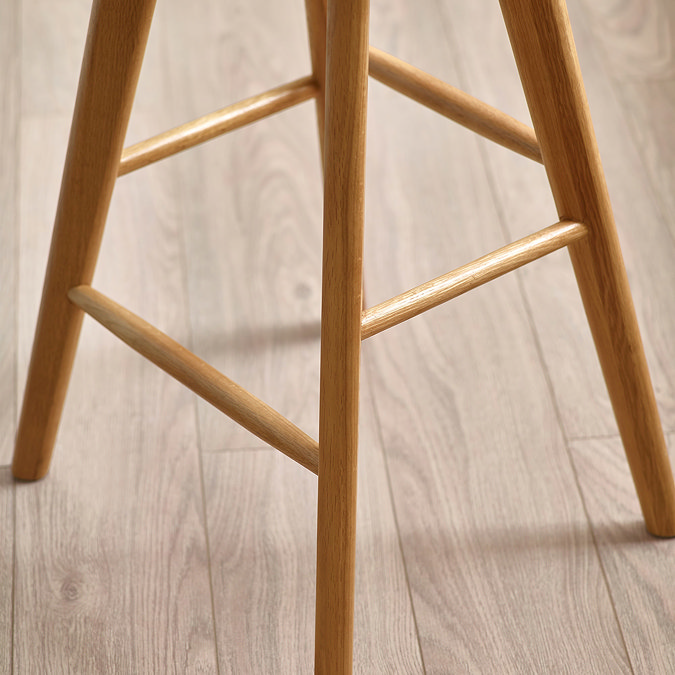 close up image of criss-crossed underneath of light oak wooden bar stool