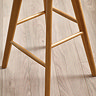 close up image of criss-crossed underneath of light oak wooden bar stool