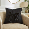 image of black velvet cushion with bow on front, sat on cream armchair