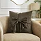image of square chocolate brown cushion with velvet bow on a cream armchair
