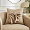 image of natural coloured square cushion with velvet bow on front, sat on a cream armchair