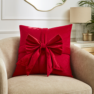 image of red velvet cushion with front bow detail on a cream armchair