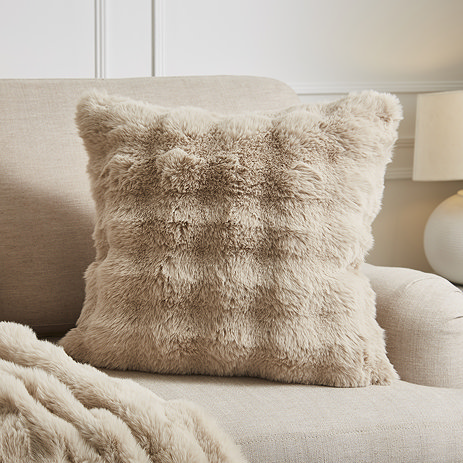 image of taupe coloured faux fur bubble cushion on a cream armchair