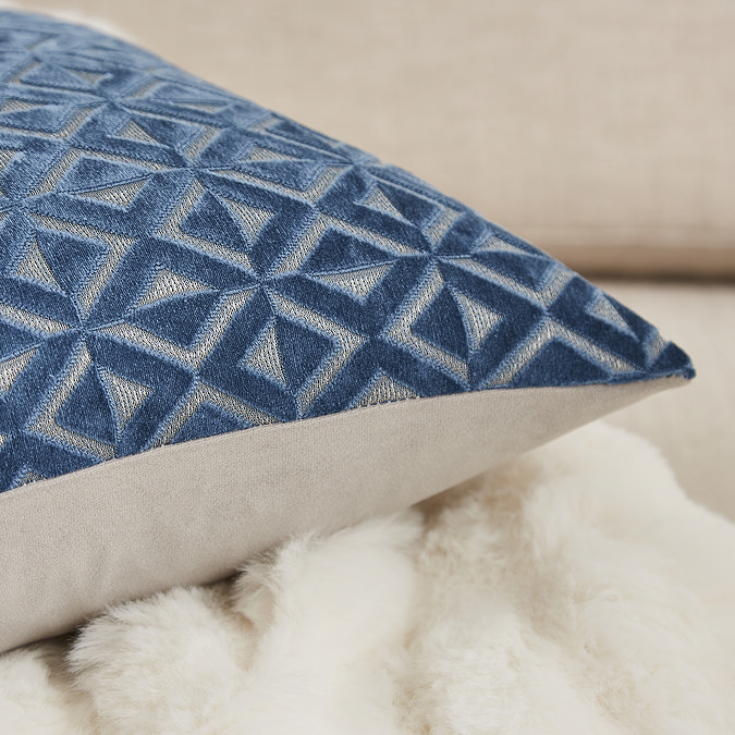 close up image of blue diamond pattern fronted cushion, with cream back