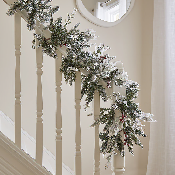 snow-dusted wreath with red berries, draped over the handrail of a bannister