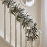 snow-dusted wreath with red berries, draped over the handrail of a bannister
