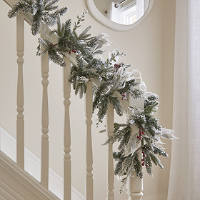 snow-dusted wreath with red berries, draped over the handrail of a bannister
