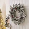 snow-dusted green wreath with red berries, hung on the back of a white living room door