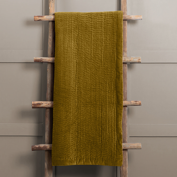 mustard yellow velvet throw hung over rustic ladder