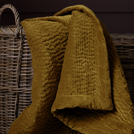 close up on mustard yellow velvet throw in whicker basket