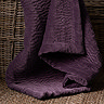 close up on plum coloured velvet throw in whicker basket