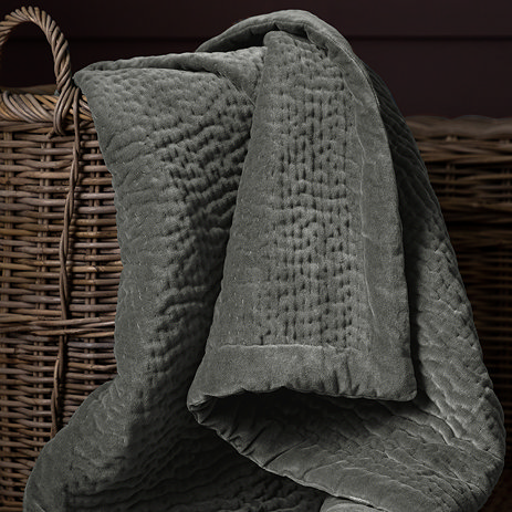 close up on steel grey velvet throw in whicker basket
