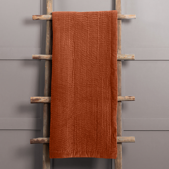 sunset orange throw folded and hung over rustic ladder