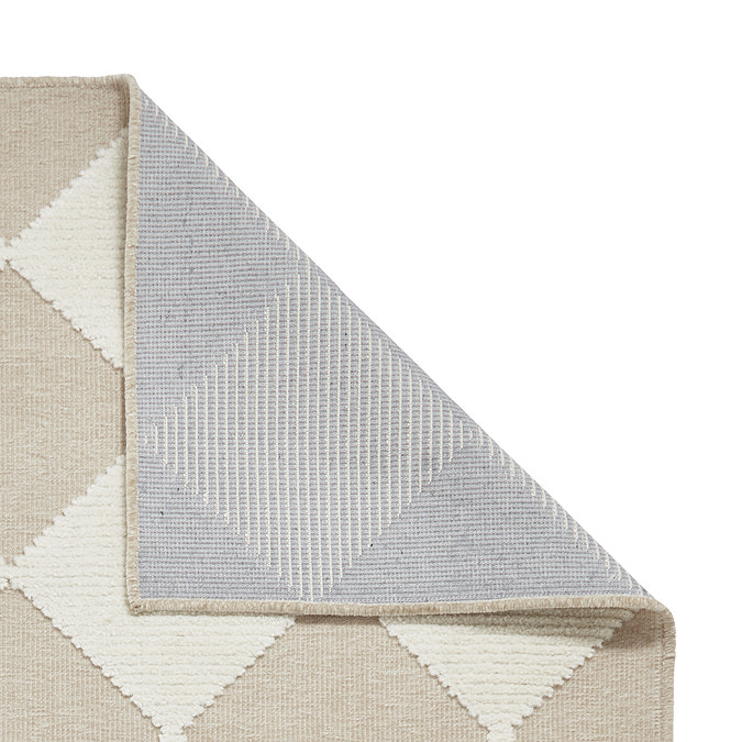 image of white and beige checkered rug folded over in corner to show floor-facing material
