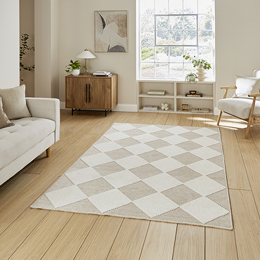 angled image of diamond checkered rug in beige and white in front of cream sofa on wooden flooring