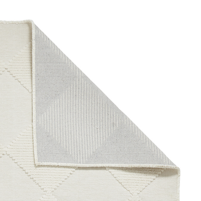 image of cream checkered rug folded over in corner to show floor-facing material underneath