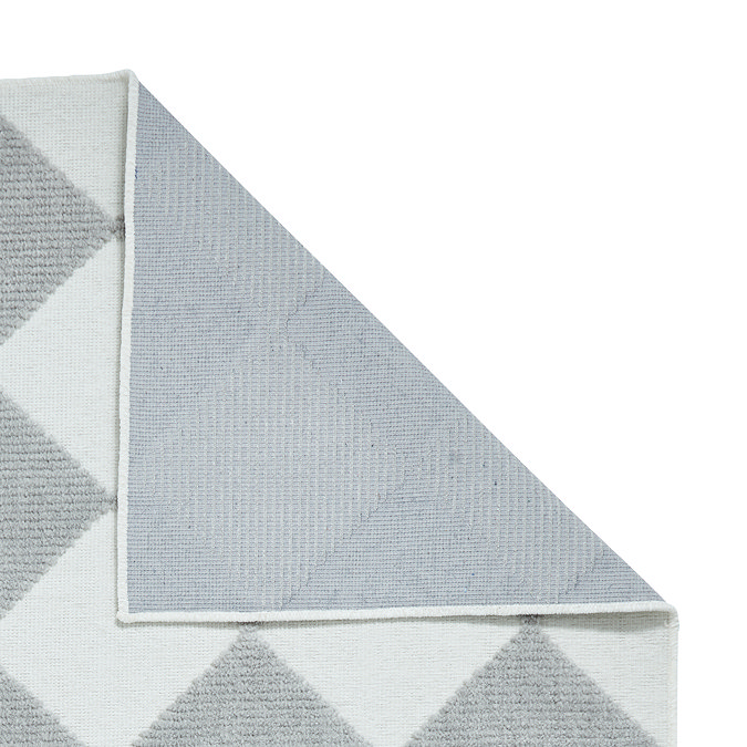 image of grey and cream diamond rug folded over at corner to show floor-facing material underneath