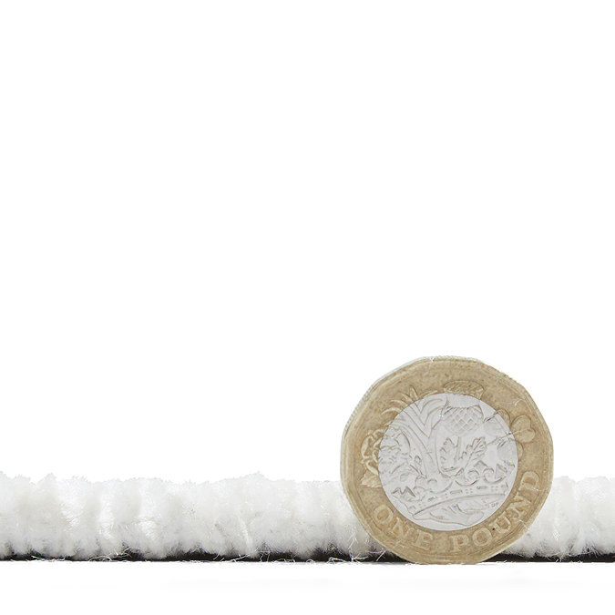 side on image of rug laid flat with pound coin stood up next to it to show rug as half the height of coin