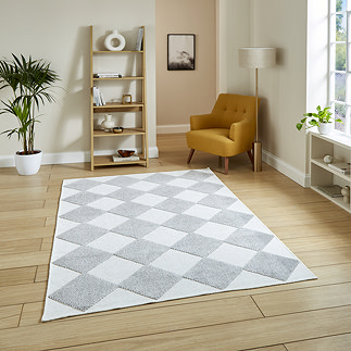 image of cream and grey diamond checkered rug on light wooden flooring of modern loft apartment