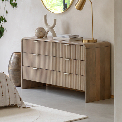 image of six drawer mango wood chest in a bedroom, with a brass lamp and decorative accessories on top