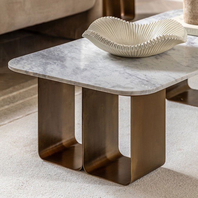 close up on gold geometric base of coffee table with smooth marble top