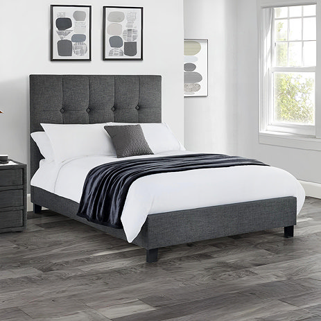 image of slate grey fabric bed with plush high headboard, on dark grey flooring of modern bedroom