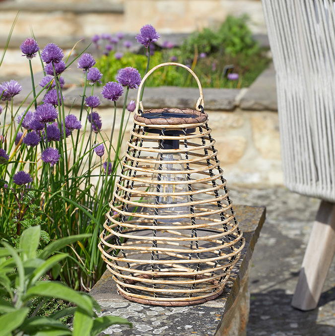 image of rattan outdoor lantern on stone bench, during the day
