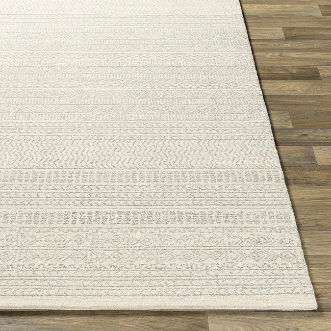 image of corner of ivory wool rug laid flat on dark wood flooring to show thickness
