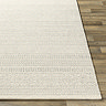 image of corner of ivory wool rug laid flat on dark wood flooring to show thickness