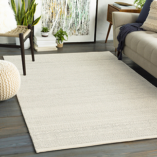 image of ivory wool rug with subtle grey pattern, on dark wood floor of living room next to ivory sofa
