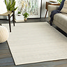 image of ivory wool rug with subtle grey pattern, on dark wood floor of living room next to ivory sofa