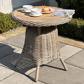 image of round wood-topped bistro table on garden patio with coffee and magazine on top of it