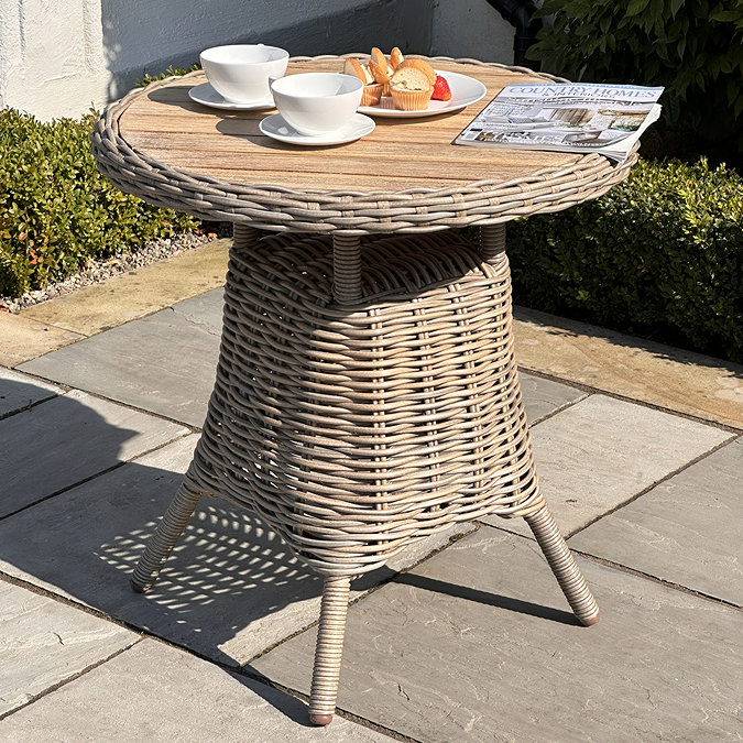 image of round wood-topped bistro table on garden patio with coffee and magazine on top of it