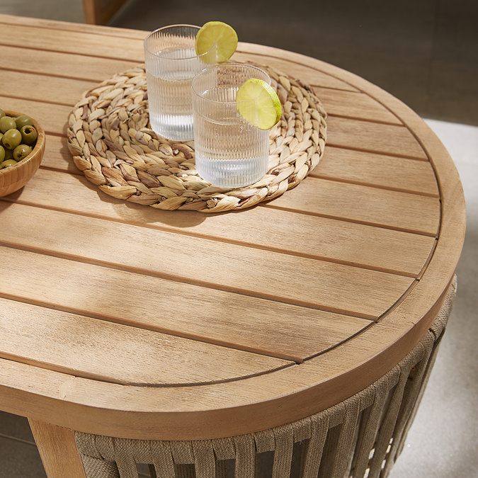 close up image of warm brown wooden table with two glasses of lemonade on top of a rattan round coaster