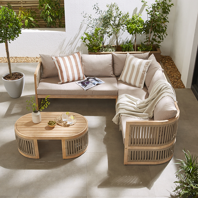 image taken from slightly above of corner sofa set with cream cushions and warm brown curved edges, outside house on a patio