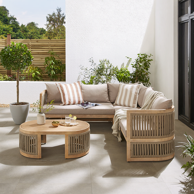 image of corner sofa on a patio outside house, with curved edges in warm brown wood and matching table with lemonade on top