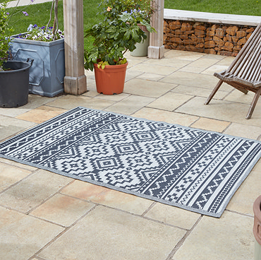 image of slate grey oriental patterned rug on grass with picnic basket