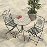 image of cast iron bistro set with potted plant in background, on pale patio