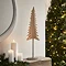 medium whitewashed wooden tree on stand, on a light oak mantlepiece next to pillar candles