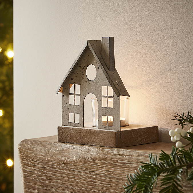 metal tealight with glass votive, stood on the end of a light oak mantlepiece.
