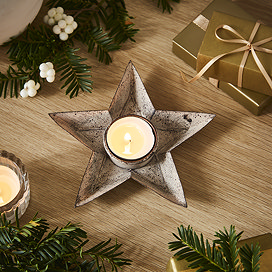 metal star tealight with glass votive, lit on a sideboard with garlands, shot from above.