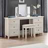 image of off-white dressing table with silver mirror on top and stool pushed slightly underneath