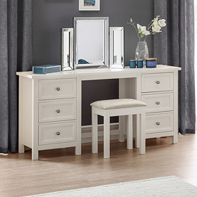 image of off-white dressing table with silver mirror on top and stool pushed slightly underneath