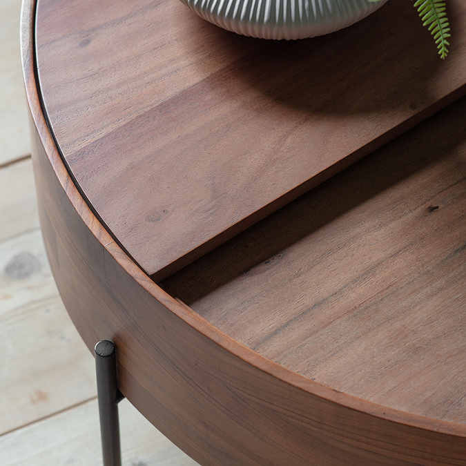 close up on top of round coffee table, with a semicircle panel that moves to conceal storage inside