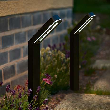 image of modern stake lights on the border of a garden pathway, emitting cool white light