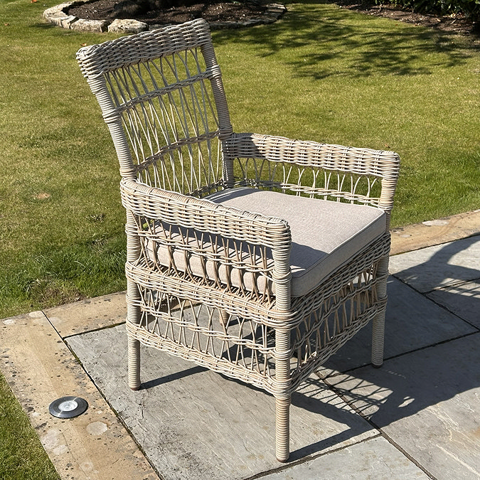 image of beige wicker chair with plush seat cushion on patio alone